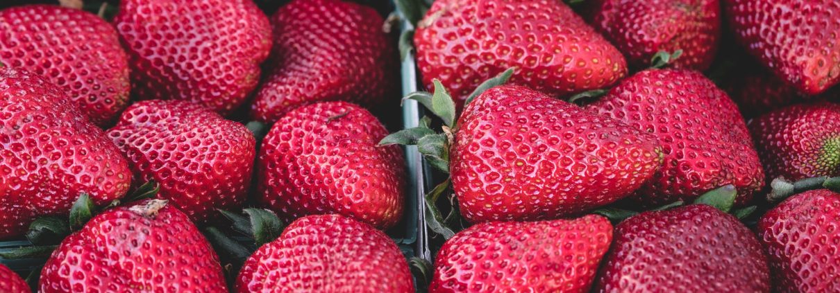 Close-up of many ripe red strawberries with green leaves, vibrant and fresh